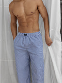 A man standing in front of a curtain is wearing lounge pants by One Dna brand