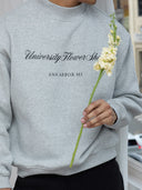 Close-up of male model with flower wearing University Flower Shop Ann Arbor mock neck sweatshirt