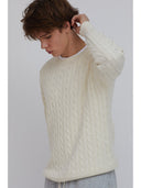 A detailed shot of a man wearing a cream cable knit sweater by One Dna brand