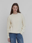 A model wearing women's cotton cable knit sweater in cream by One Dna brand