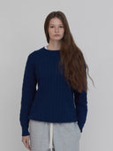 A model wears women's cotton cable knit sweater in navy by One Dna brand