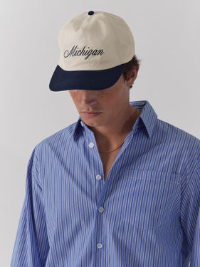 white and navy hat with michigan in cursive font by one dna ann arbor