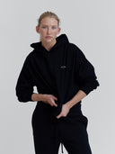a women wears black french terry hoodie with one dna earth logo