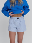 A women wears three-pocket board shorts in white pinstripe by One Dna